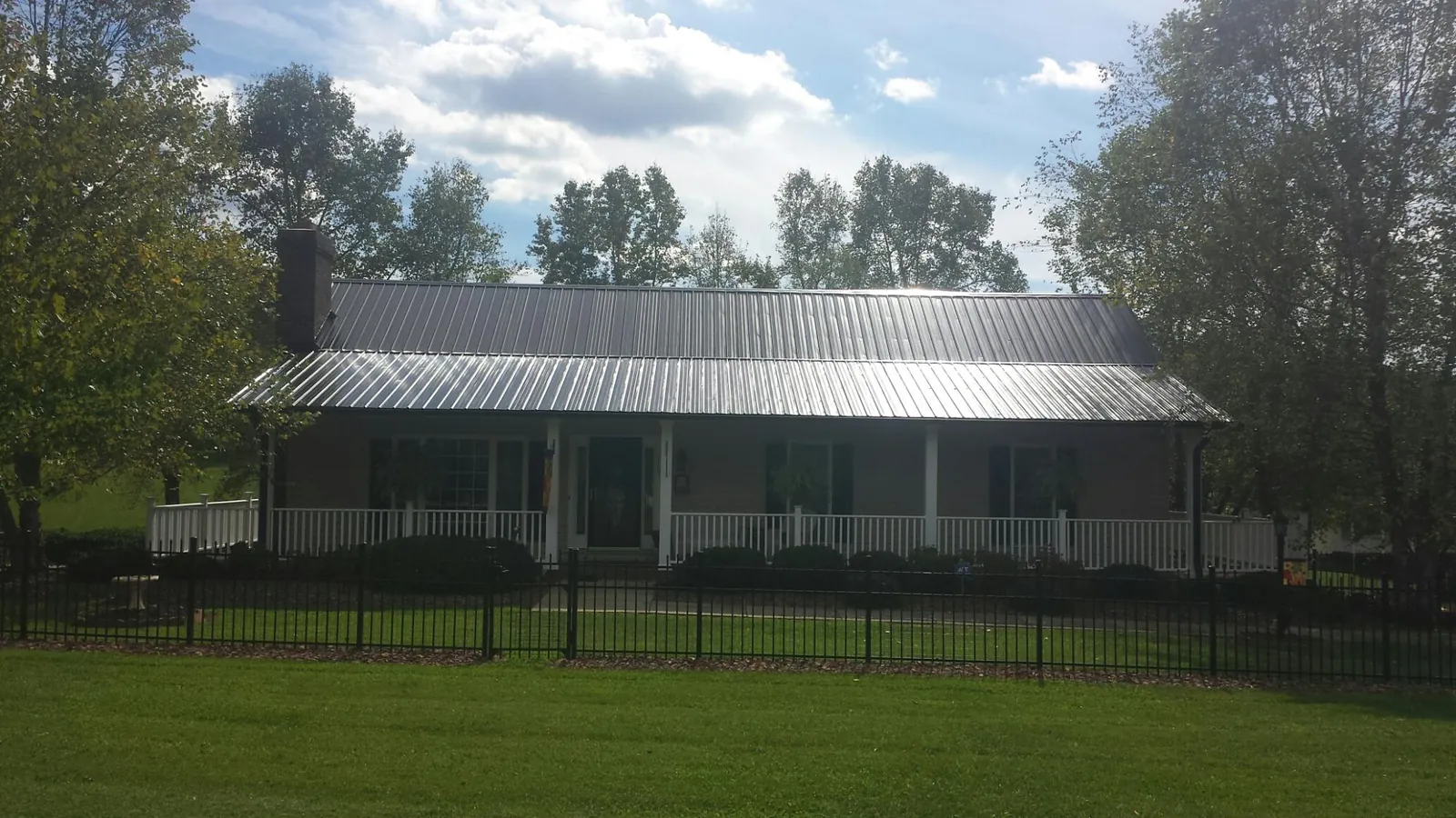 Gray metal roof on a brick ranch with a full width front porch — Gutter Guard Installation work by our crew in Wellington